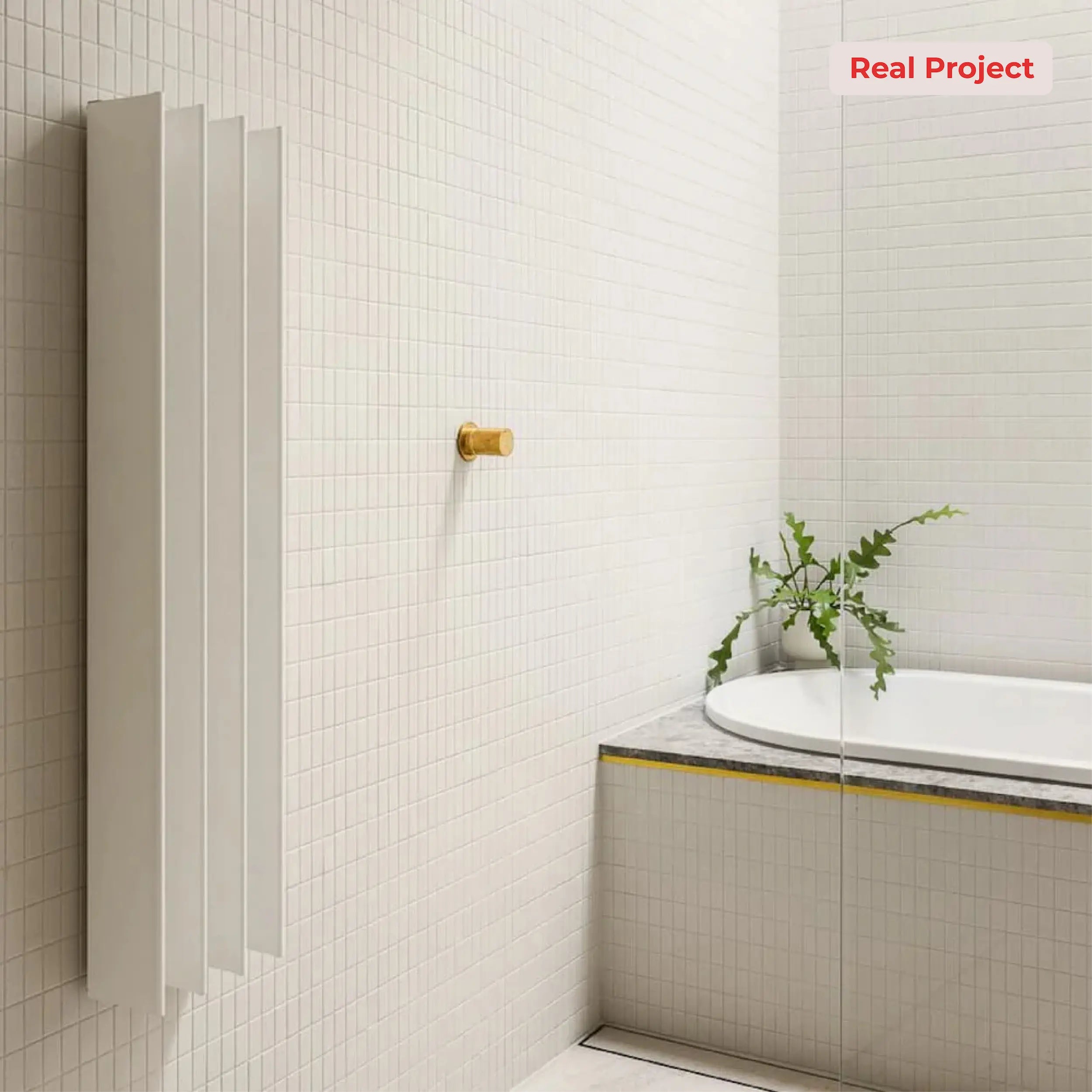 Bathroom interior with a heated towel rail, bathtub, and plant on a mosaic tiled wall