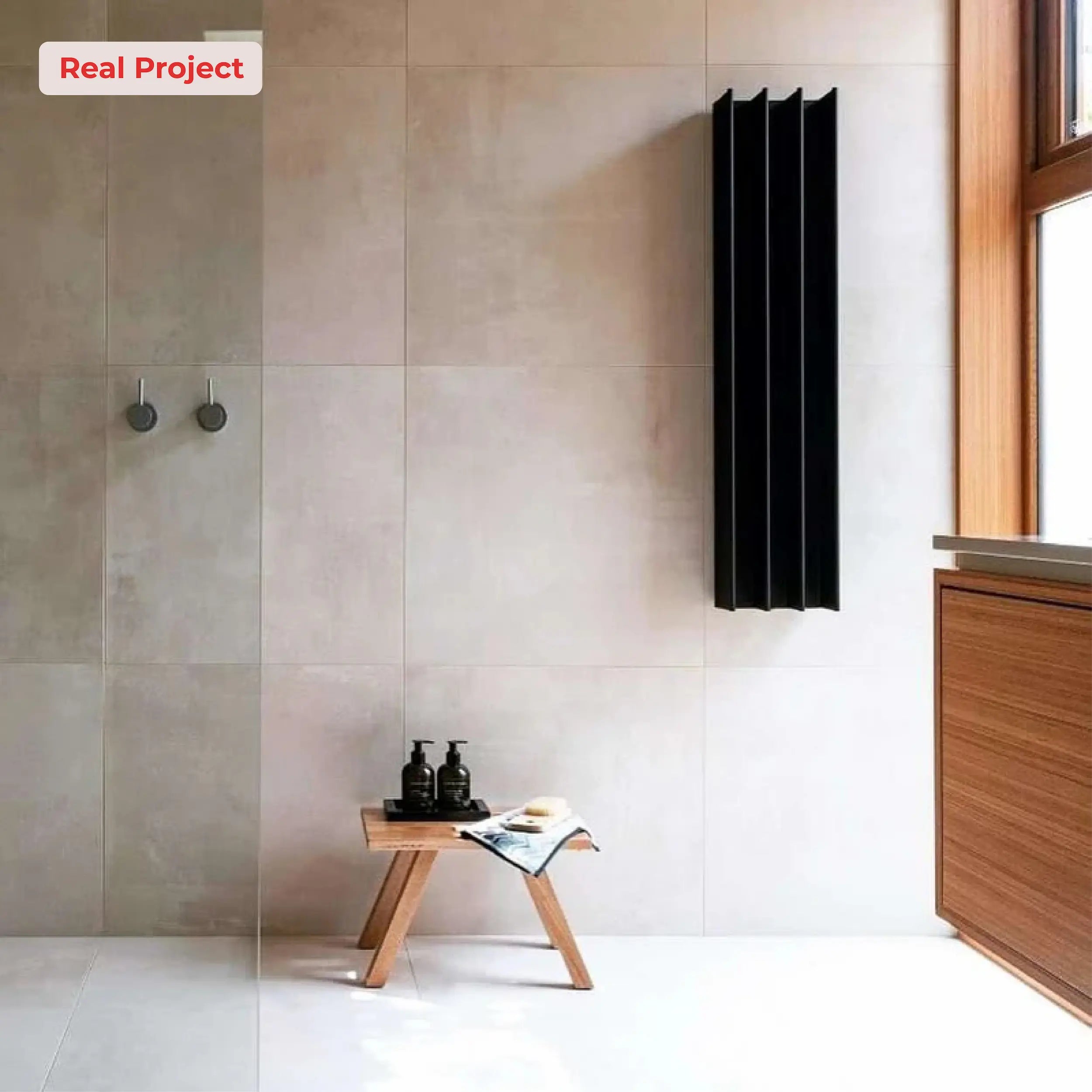 Modern bathroom with a black vertical heated towel rail on a tiled wall.