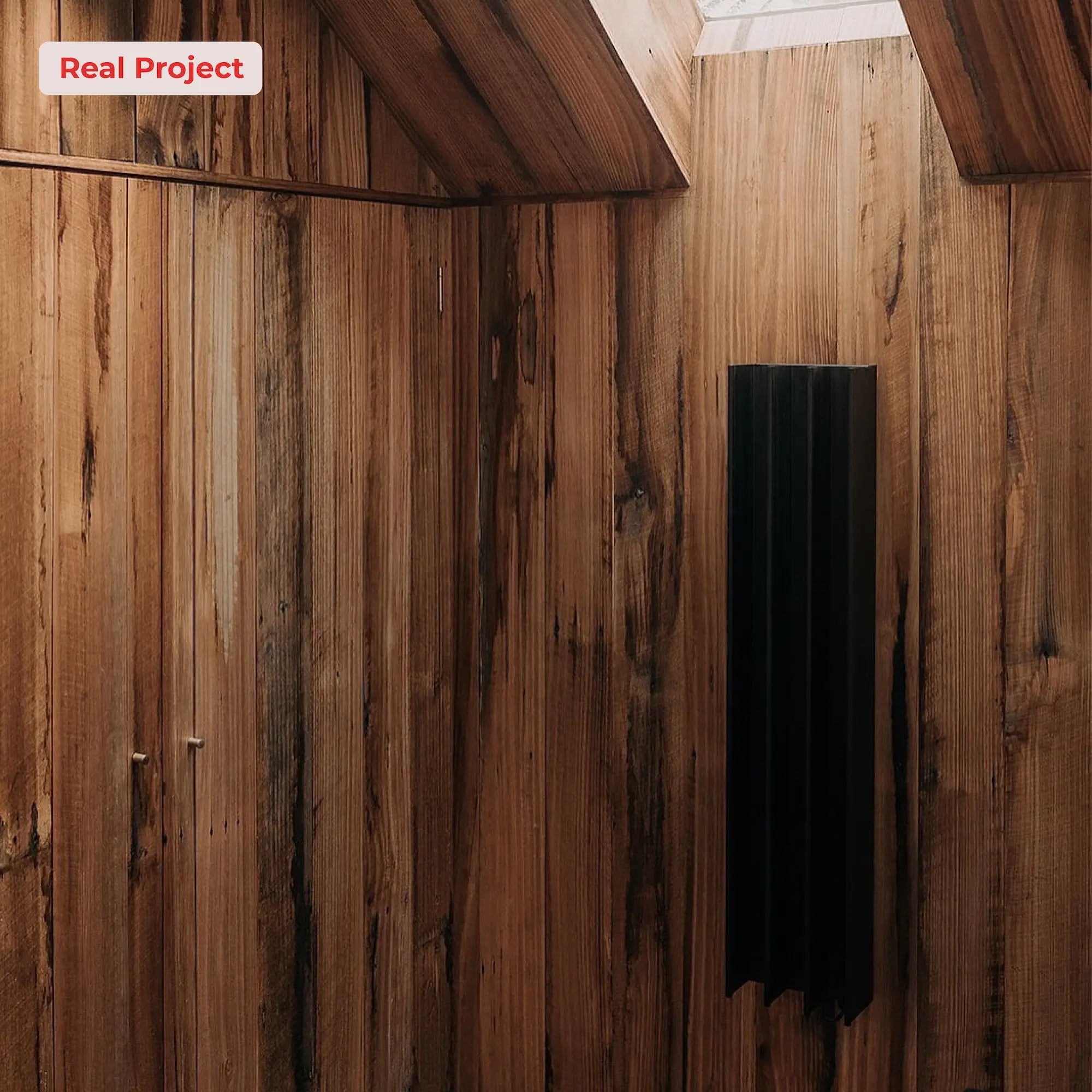 Wooden cabin wall with a black heated towel warmer.